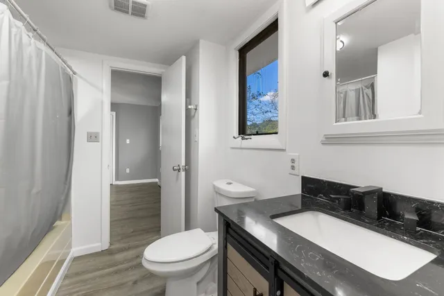 a bathroom with a granite countertop toilet sink and mirror