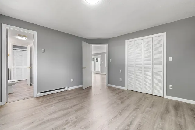 an empty room with wooden floor & windows and bathroom