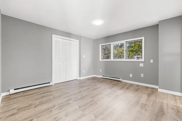 an empty room with wooden floor and windows