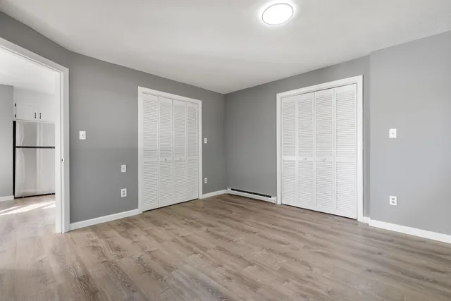 a view of an empty room with wooden floor and closet
