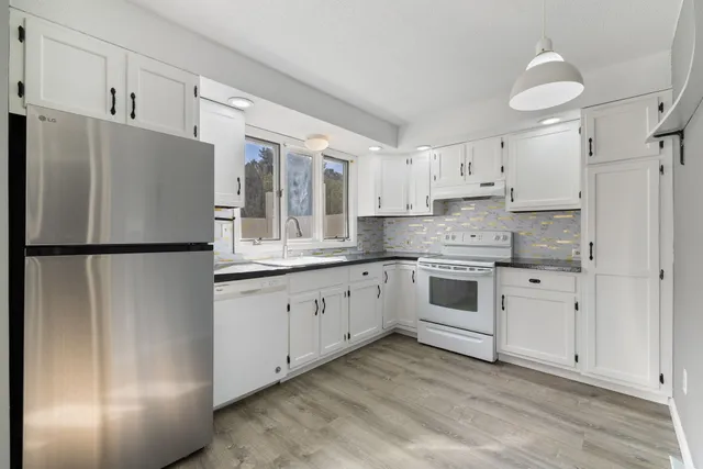 a kitchen with granite countertop white cabinets and refrigerator