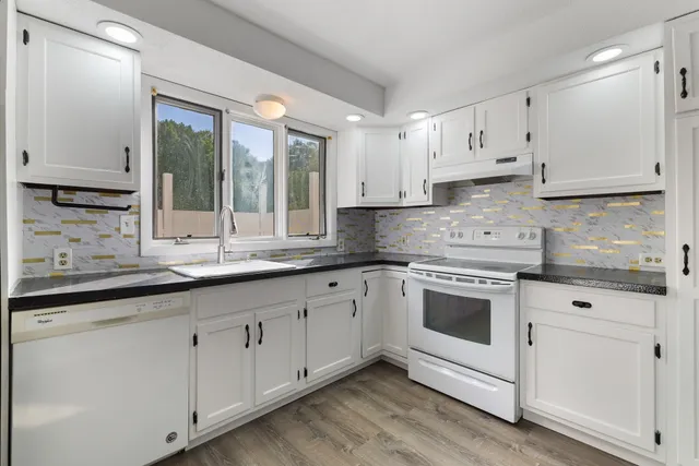 a kitchen with granite countertop white cabinets and white appliances