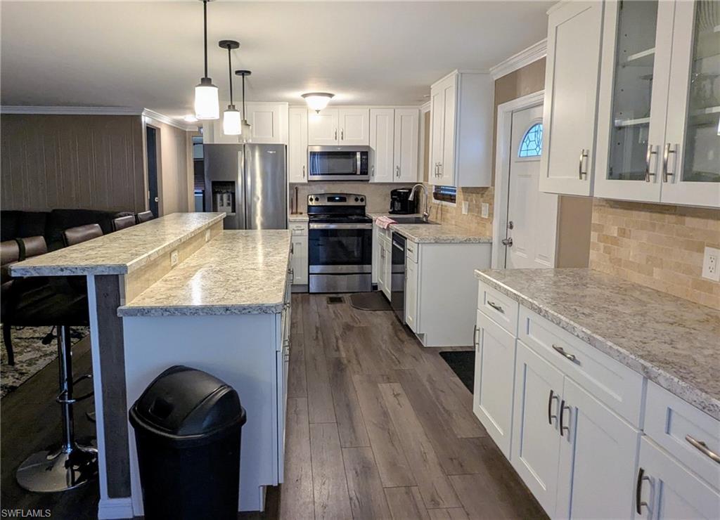 9269 Lord Road Bonita Springs, FL 34135 - Photo 11 of 20 a kitchen with granite countertop a stove top oven a sink dishwasher and a fireplace with wooden floor