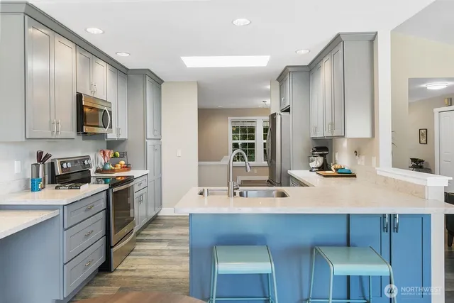 a kitchen with kitchen island granite countertop a sink appliances cabinets and a counter top space