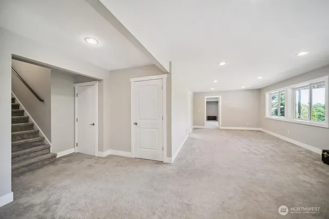 a view of an empty room with wooden floor and windows