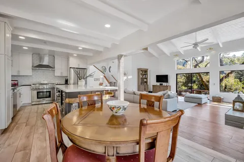 a living room with stainless steel appliances furniture a dining table and chairs