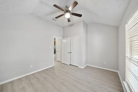 an empty room with wooden floor fan and windows