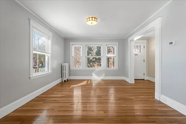 a view of an empty room with wooden floor and a window