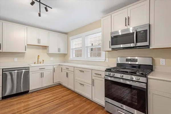 a kitchen with stainless steel appliances white cabinets granite counter tops and a window