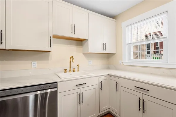 a kitchen with white cabinets appliances a sink and a window