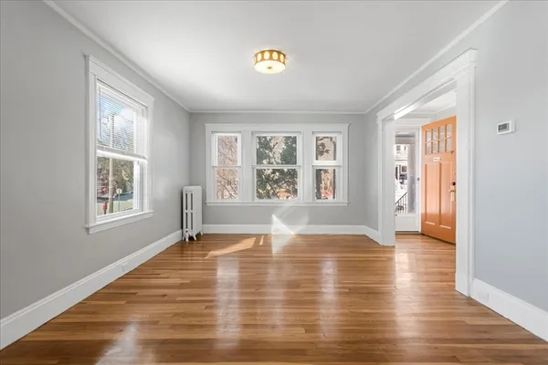 a view of empty room with wooden floor and fan