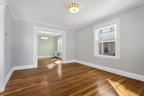 a view of an empty room with window and wooden floor