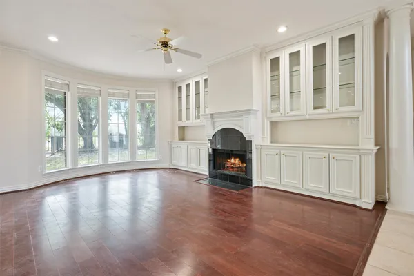 a view of an empty room with a window and wooden floor