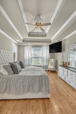 a bedroom with a bed a flat screen tv and a chandelier