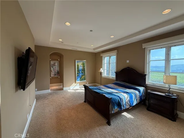 a bedroom with a bed and a flat tv screen on dresser