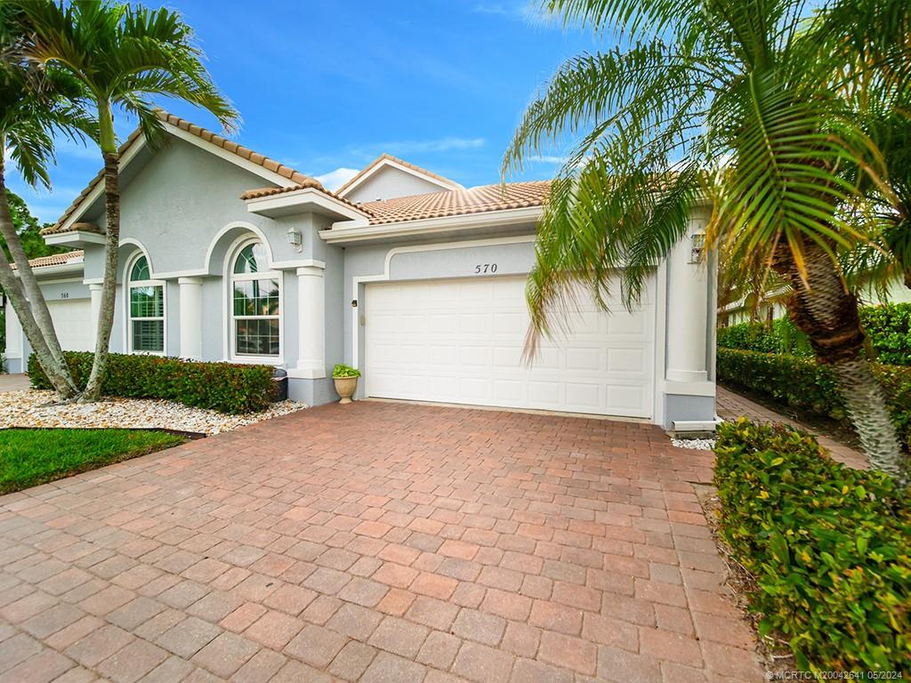 a view of a white house with a small yard and palm trees
