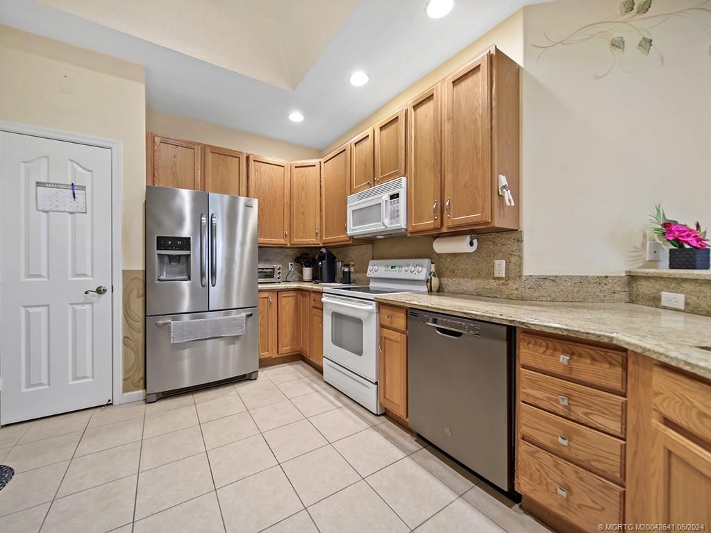 570 Northwest Red Pine Way Jensen Beach, FL 34957 - Photo 3 of 19 a kitchen with a refrigerator sink and cabinets