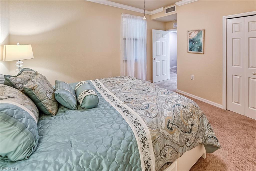 9528 Avellino Way, Unit 2515 Naples, FL 34113 - Photo 18 of 35 a bedroom with a bed and a lamp