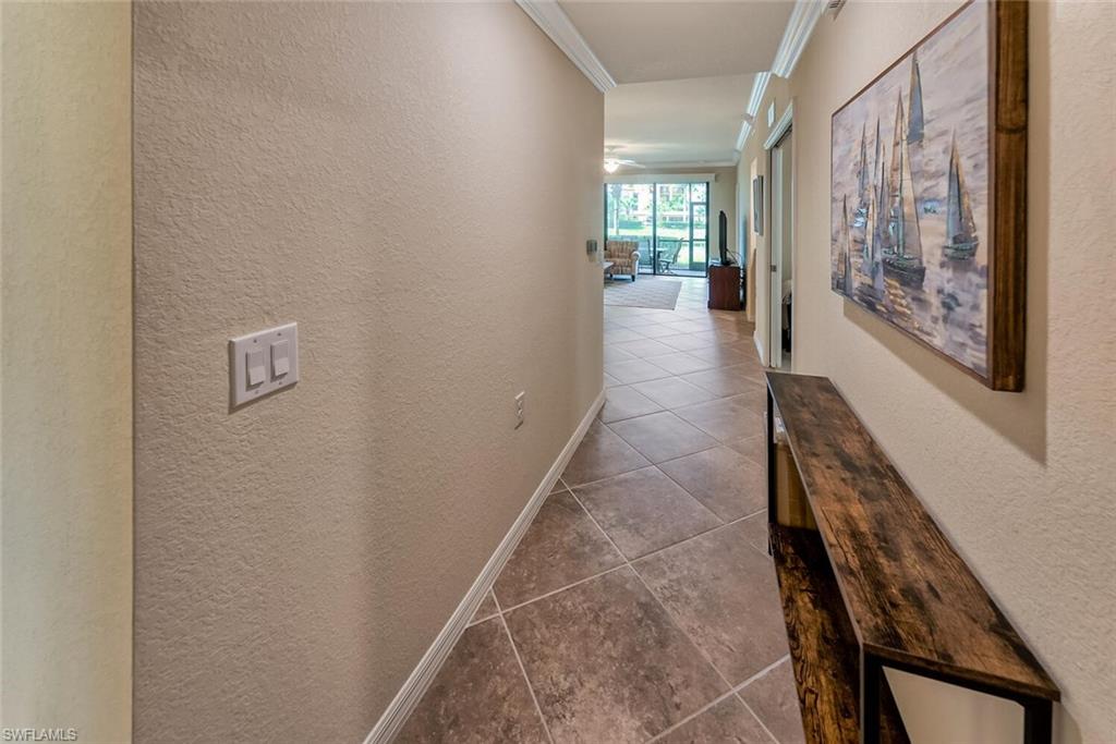 9528 Avellino Way, Unit 2515 Naples, FL 34113 - Photo 4 of 35 a hallway with a wooden cabinet and couches with wooden floor