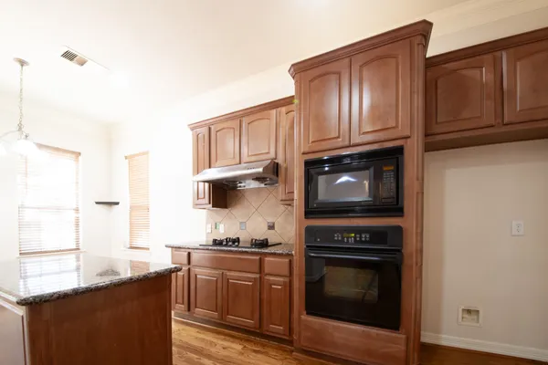 a kitchen with granite countertop cabinets stainless steel appliances and a wooden floor