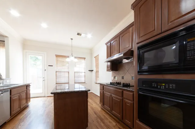 a spacious bedroom with a bed and dresser with wooden floor
