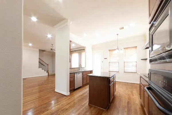 a kitchen with granite countertop appliances cabinets and a wooden floor