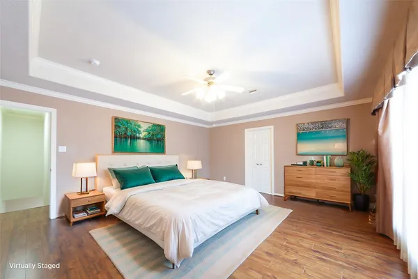a spacious bedroom with a bed and dresser with wooden floor