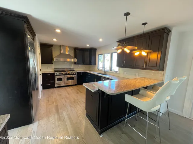 a kitchen with stainless steel appliances granite countertop a sink a stove and a wooden floors