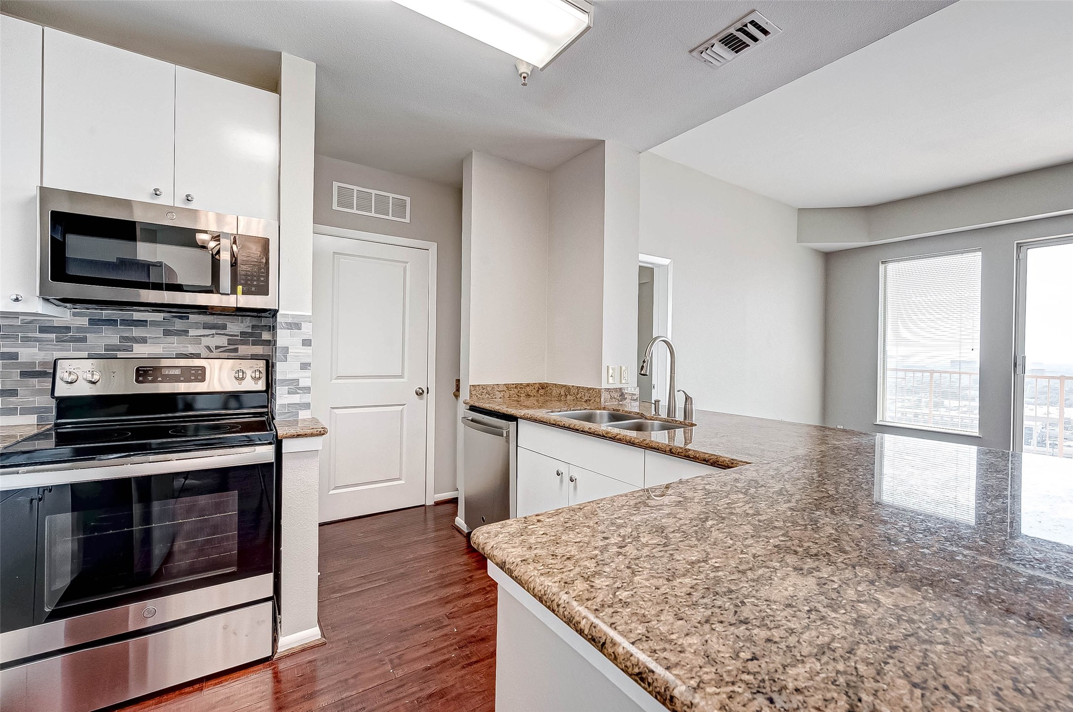 3505 Sage Road, Unit 2106 Houston, TX 77056 - Photo 5 of 31 This modern kitchen features sleek stainless steel appliances, granite countertops, and a stylish tile backsplash. The open layout offers a spacious feel, enhanced by ample natural light from the adjacent windowed area. Perfect for both cooking and entertaining.