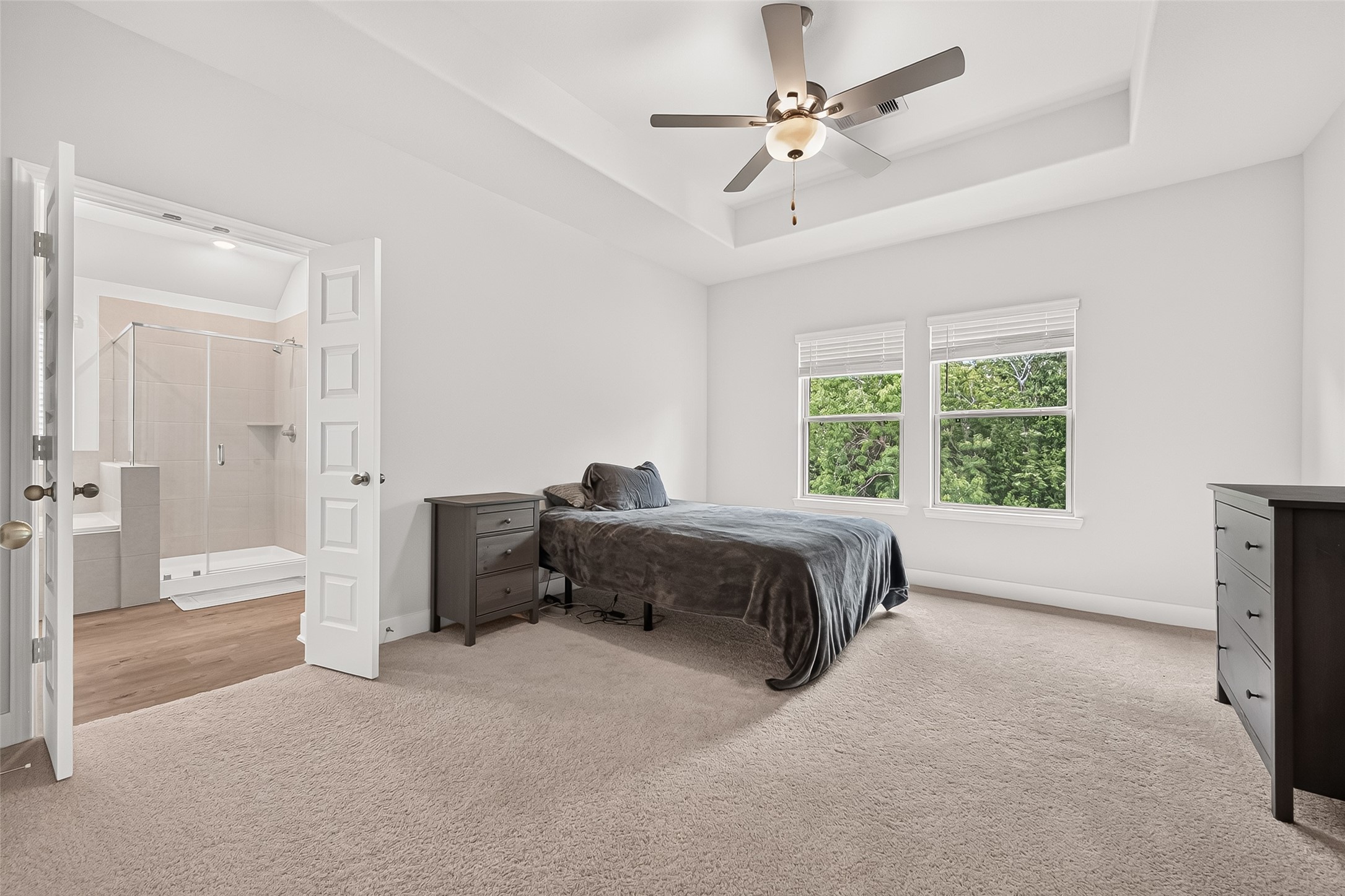 4004 Baja Lane Houston, TX 77045 - Photo 17 of 34 An impressive primary suite with exceptional style. From the architectural tray ceiling accent to the generous wall of windows, this large bedroom feels incredibly bright and inviting. Designed for ultimate comfort, this beautifully maintained space is ready to easily adapt to your personal style.