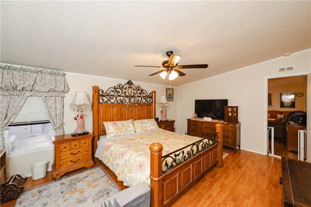 18488 Golf Course Avenue Wikieup, AZ 85360 - Photo 12 of 41 MAIN HOUSE: Bedroom with wood finished floors, a textured ceiling, vaulted ceiling, crown molding, and a ceiling fan