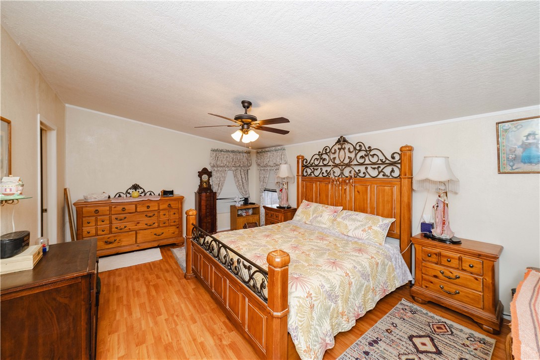 18488 Golf Course Avenue Wikieup, AZ 85360 - Photo 13 of 41 MAIN HOUSE: Bedroom featuring light wood-style flooring, a textured ceiling, a ceiling fan, and ornamental molding