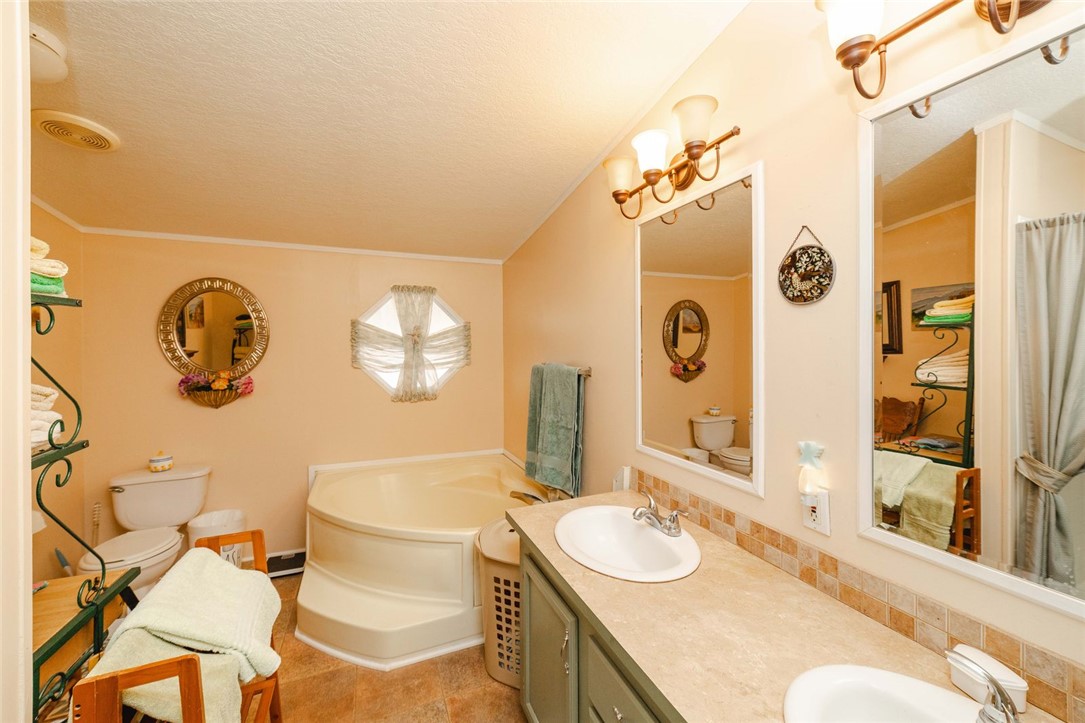 18488 Golf Course Avenue Wikieup, AZ 85360 - Photo 14 of 41 Bathroom with double vanity, a garden tub, tasteful backsplash, a textured ceiling, and crown molding