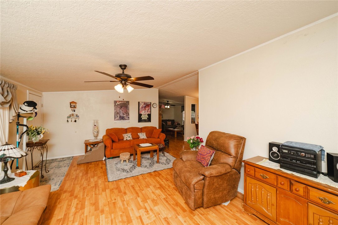 18488 Golf Course Avenue Wikieup, AZ 85360 - Photo 7 of 41 Living area featuring lofted ceiling, light wood-style flooring, a ceiling fan, and a textured ceiling