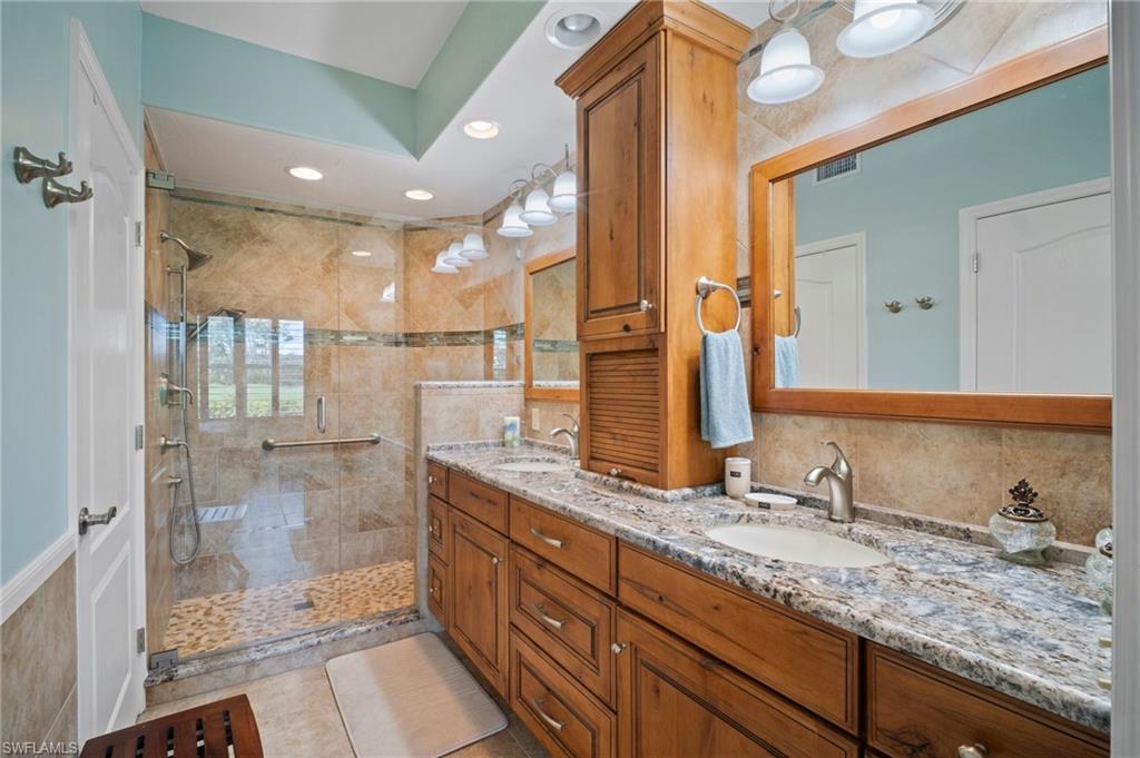 9281 Spring Run Boulevard, Unit 2607 Estero, FL 34135 - Photo 33 of 46 a bathroom with a granite countertop sink mirror and shower