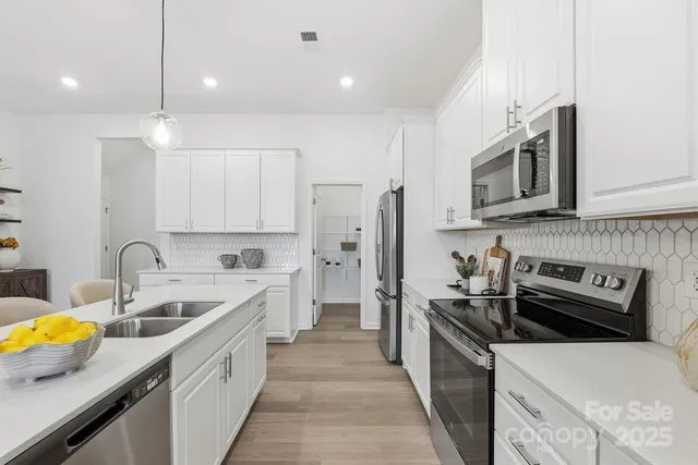 a kitchen that has a lot of cabinets a sink and wooden floor