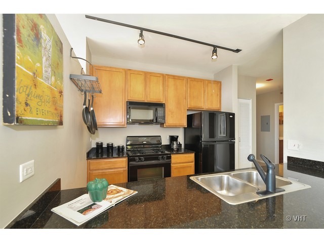 210 South Desplaines Street, Unit 910 Chicago, IL 60661 - Photo 3 of 12 a kitchen with stainless steel appliances kitchen island granite countertop a refrigerator a stove top oven and a sink with granite countertops