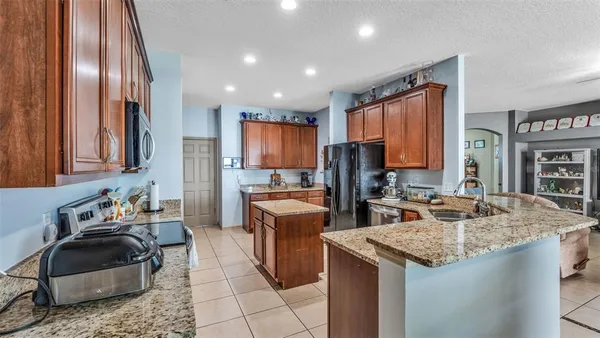a kitchen with granite countertop kitchen island stainless steel appliances a sink stove and refrigerator