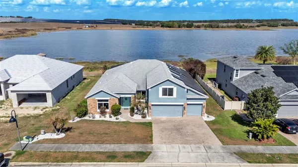 an aerial view of a house with a yard and lake view