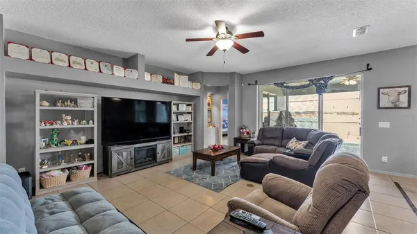 a living room with furniture a ceiling fan and a flat screen tv