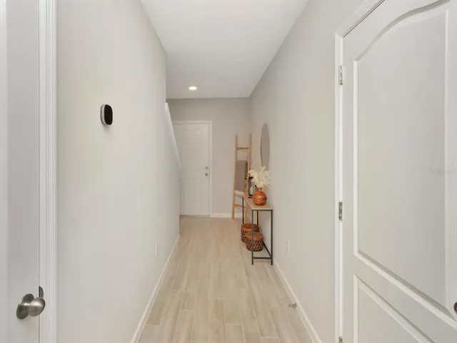 a view of a hallway with wooden floor and a bathroom