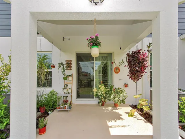 a patio with table and chairs and potted plants