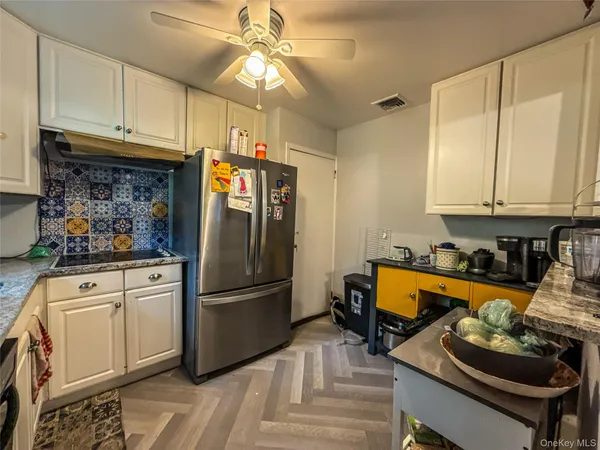 a kitchen with stainless steel appliances granite countertop a refrigerator stove and white cabinets