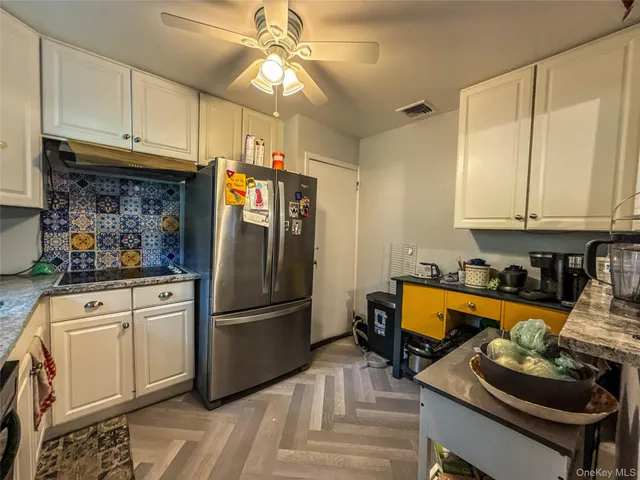 a kitchen with stainless steel appliances granite countertop a refrigerator stove and white cabinets