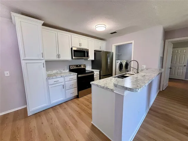 a kitchen with kitchen island granite countertop a sink wooden cabinets and stainless steel appliances