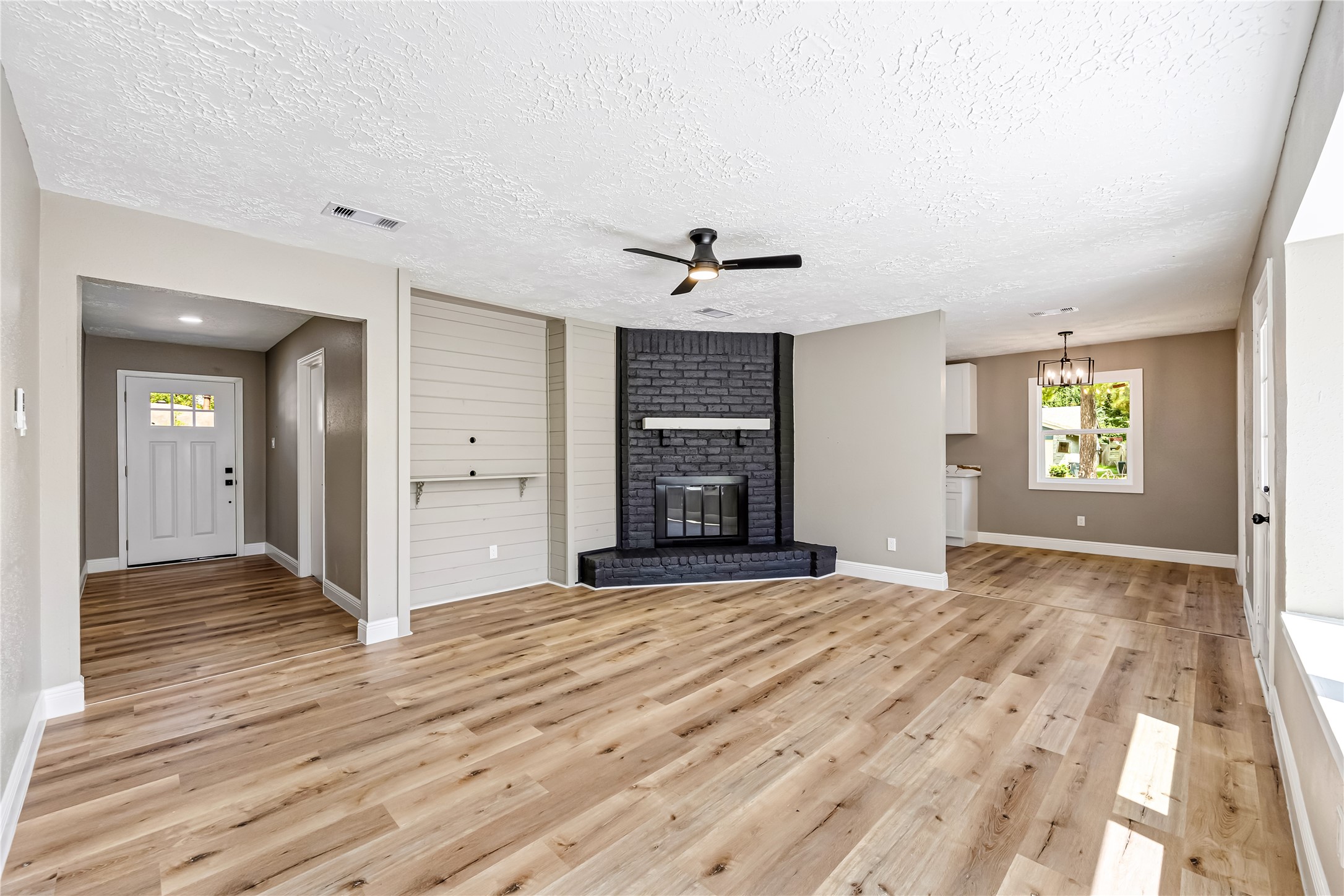 4534 Rosegate Drive Spring, TX 77373 - Photo 6 of 24 Spacious living area with warm wood-look flooring, a striking dark brick fireplace, neutral finishes, and abundant natural light. The open layout flows easily into the dining and kitchen areas, creating a comfortable and inviting space for everyday living and entertaining.