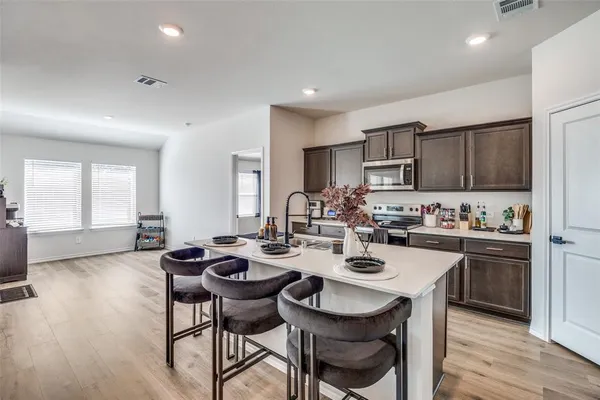 a open dining room with stainless steel appliances kitchen island granite countertop a stove a sink a dining table and chairs