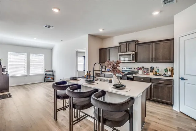 a open dining room with stainless steel appliances kitchen island granite countertop a stove a sink a dining table and chairs