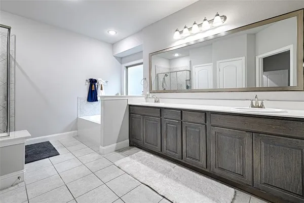 a spacious bathroom with a double vanity sink a mirror and a toilet