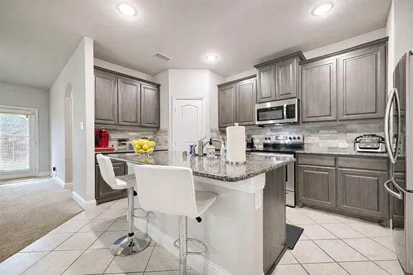 a kitchen with stainless steel appliances kitchen island granite countertop a sink and cabinets